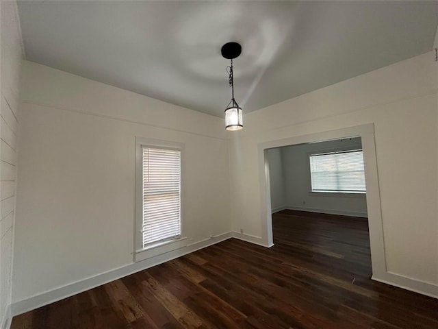 unfurnished dining area featuring dark wood-style floors and baseboards