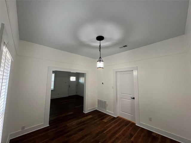 unfurnished dining area with dark wood-type flooring, visible vents, and baseboards