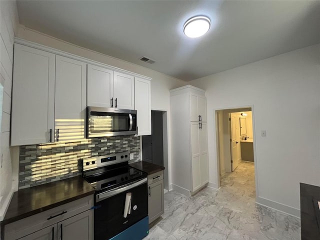 kitchen featuring tasteful backsplash, visible vents, dark countertops, appliances with stainless steel finishes, and marble finish floor