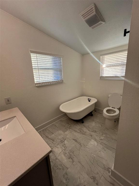 full bathroom with toilet, vanity, visible vents, vaulted ceiling, and a soaking tub