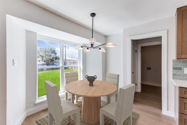 dining area featuring baseboards, light wood-style flooring, and a notable chandelier