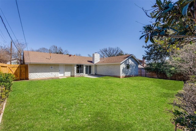 back of property featuring a fenced backyard, a lawn, and a chimney