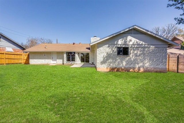 back of property featuring stone siding, a lawn, a chimney, and fence