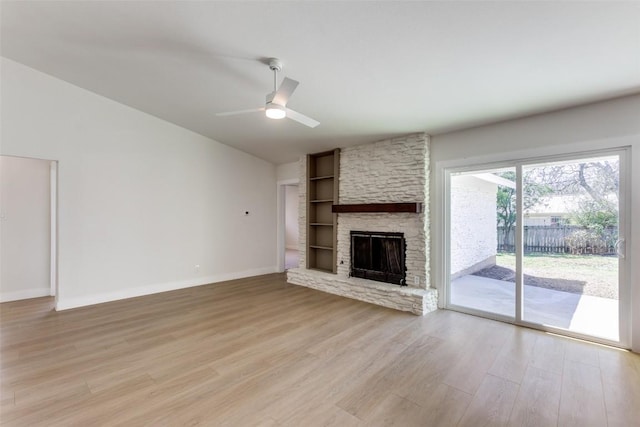 unfurnished living room with light wood-style floors, baseboards, vaulted ceiling, and a stone fireplace