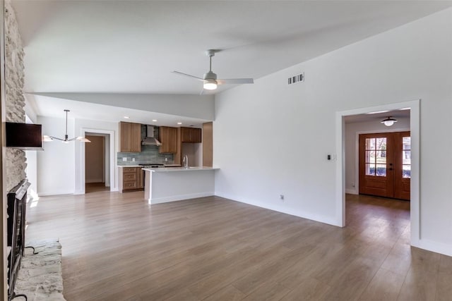 unfurnished living room featuring light wood-style floors, visible vents, a ceiling fan, and a stone fireplace