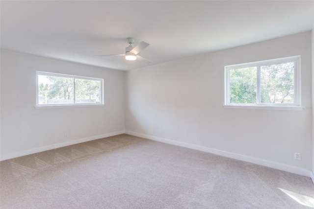 carpeted spare room featuring a ceiling fan and baseboards