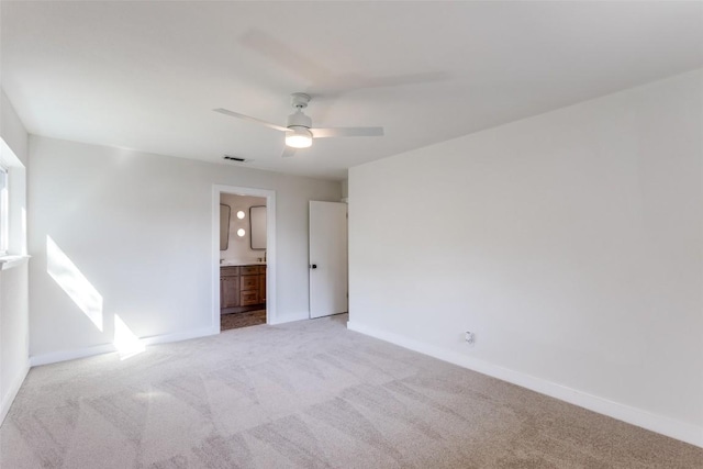 unfurnished bedroom featuring baseboards, ensuite bath, visible vents, and light colored carpet