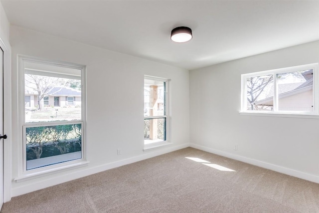 carpeted empty room featuring baseboards and a healthy amount of sunlight