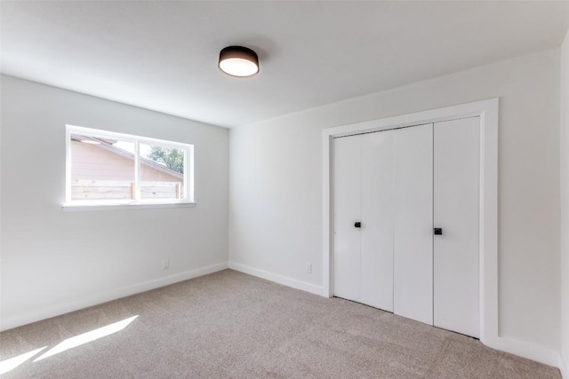 unfurnished bedroom with carpet floors, a closet, and baseboards