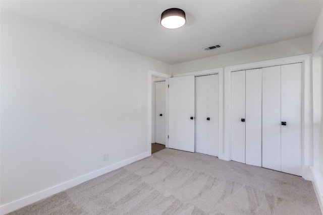 unfurnished bedroom with carpet floors, baseboards, visible vents, and two closets