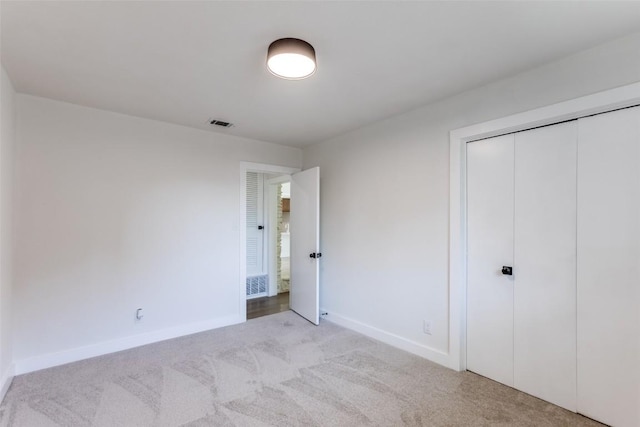 unfurnished bedroom with visible vents, baseboards, a closet, and light colored carpet