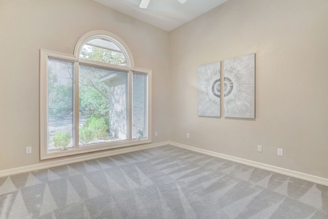 carpeted spare room with baseboards and a ceiling fan