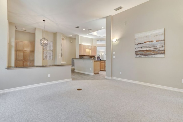 unfurnished living room featuring baseboards, a notable chandelier, visible vents, and light colored carpet