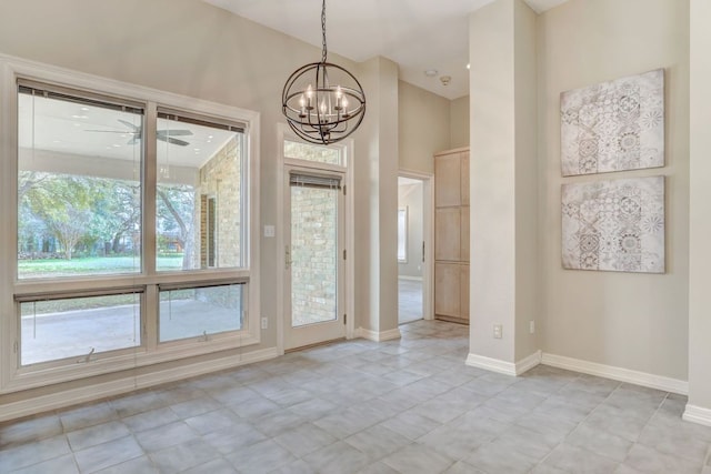 unfurnished dining area with ceiling fan with notable chandelier and baseboards