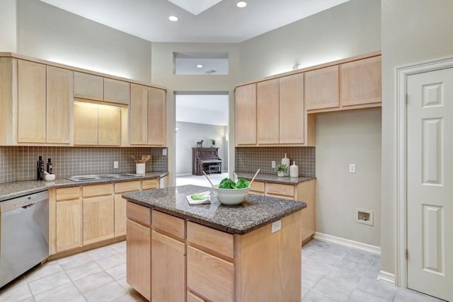 kitchen featuring dark stone counters, light brown cabinetry, and stainless steel dishwasher