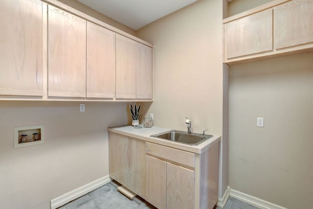 clothes washing area featuring a sink, hookup for a washing machine, cabinet space, and baseboards