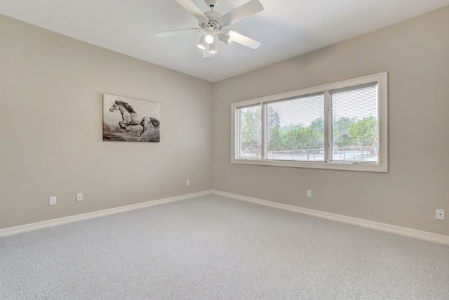 spare room with ceiling fan, light colored carpet, and baseboards