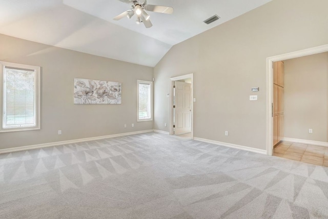 empty room with lofted ceiling, baseboards, visible vents, and light colored carpet