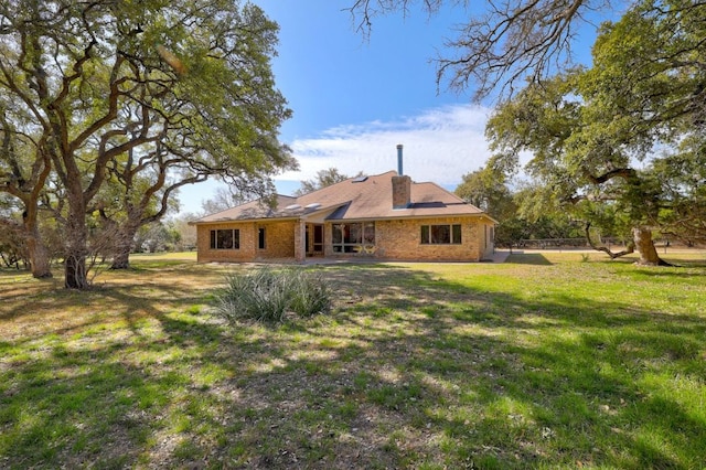 rear view of house featuring brick siding and a lawn