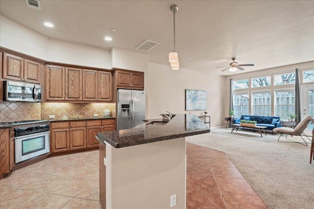 kitchen featuring light carpet, stainless steel appliances, a sink, visible vents, and decorative backsplash