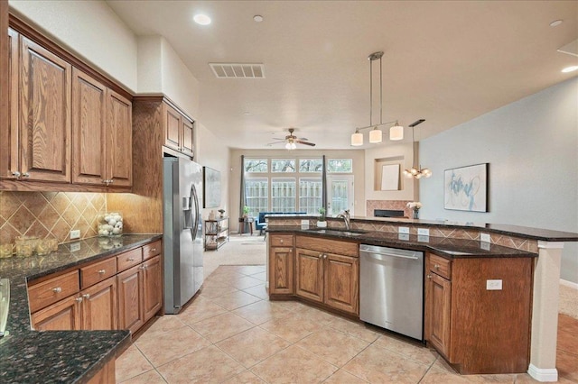 kitchen with visible vents, decorative backsplash, brown cabinets, stainless steel appliances, and a sink