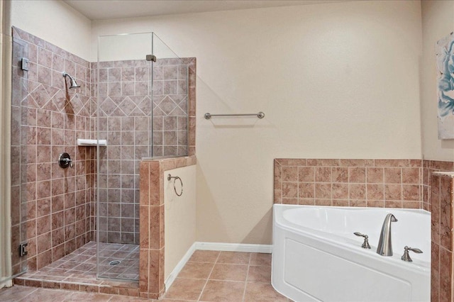 full bath featuring tile patterned flooring, tiled shower, baseboards, and a bath