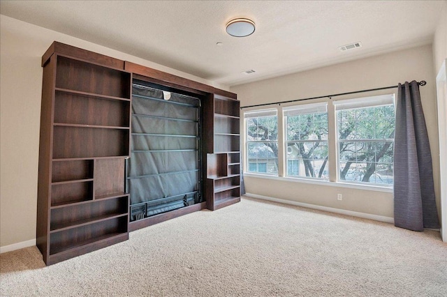 interior space featuring carpet floors, visible vents, a textured ceiling, and baseboards