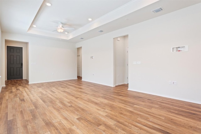 unfurnished room with a tray ceiling, light wood finished floors, recessed lighting, visible vents, and ceiling fan