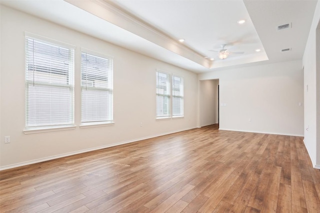 unfurnished room featuring visible vents, baseboards, a ceiling fan, light wood finished floors, and a raised ceiling