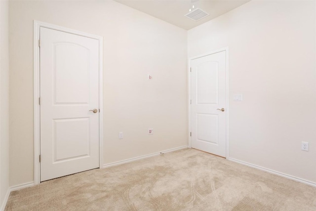 spare room featuring light colored carpet, visible vents, and baseboards