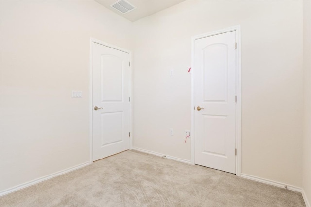 spare room with light colored carpet, visible vents, and baseboards