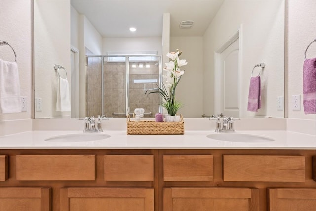 full bathroom with a sink, a shower stall, and double vanity