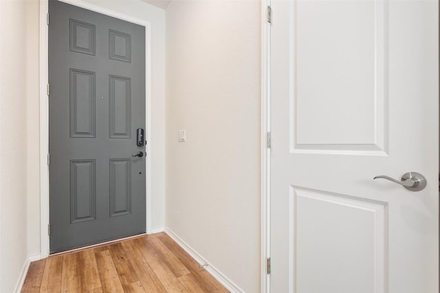 doorway featuring light wood finished floors and baseboards