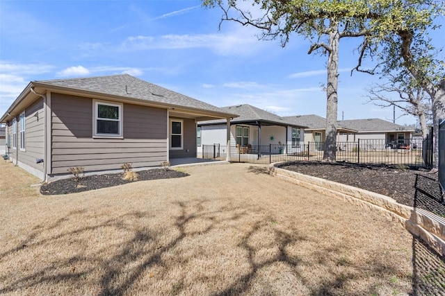 back of property with a yard, roof with shingles, fence, and a patio