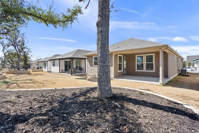 rear view of property with a patio area and roof with shingles