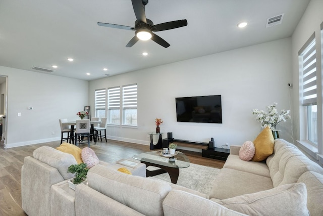 living area featuring a ceiling fan, visible vents, and wood finished floors