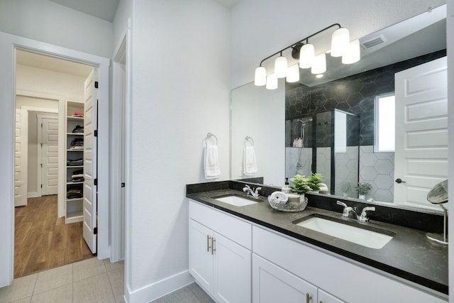 bathroom featuring a sink, a spacious closet, a shower stall, and visible vents