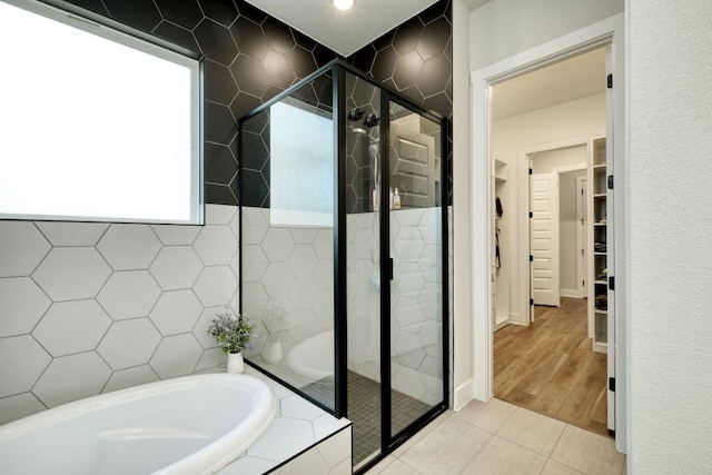 full bath featuring tile patterned floors, a spacious closet, a bath, and a stall shower