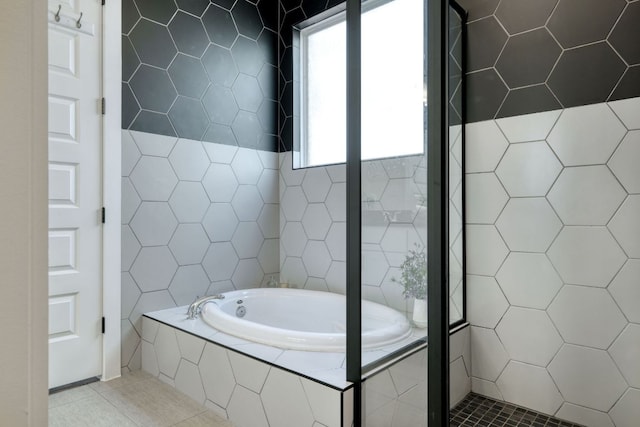 full bathroom with tile walls, tile patterned flooring, and a bath