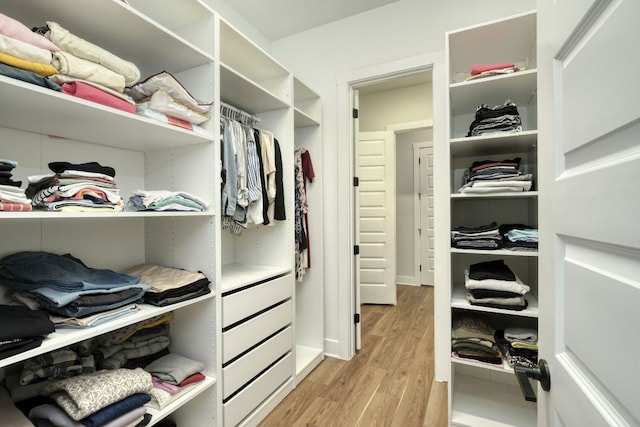 walk in closet with light wood-style floors