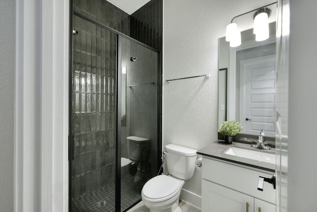 bathroom with vanity, a textured wall, toilet, and a shower stall