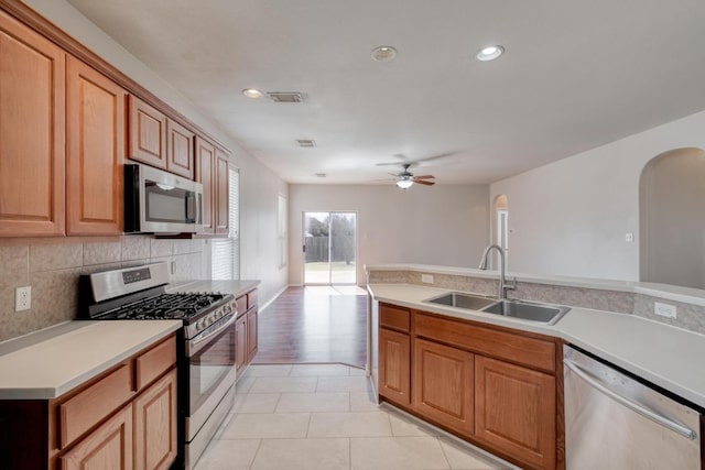 kitchen featuring tasteful backsplash, visible vents, arched walkways, appliances with stainless steel finishes, and a sink