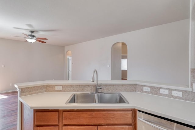 kitchen featuring ceiling fan, wood finished floors, a sink, light countertops, and stainless steel dishwasher