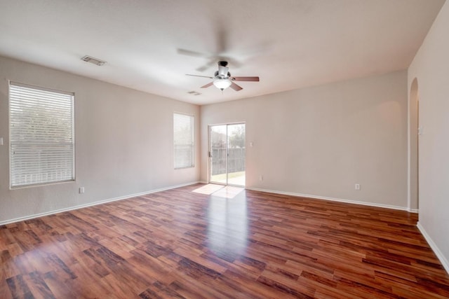 spare room with baseboards, visible vents, arched walkways, ceiling fan, and wood finished floors