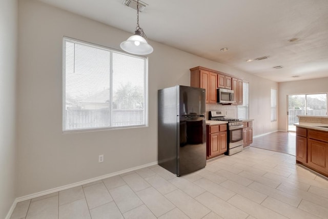 kitchen with stainless steel appliances, brown cabinetry, backsplash, and visible vents