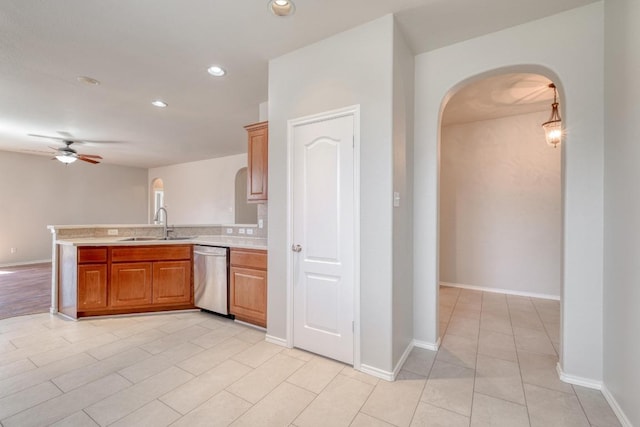 kitchen with arched walkways, a peninsula, a sink, light countertops, and stainless steel dishwasher