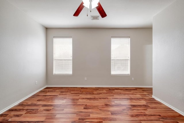 spare room featuring ceiling fan, wood finished floors, visible vents, and baseboards