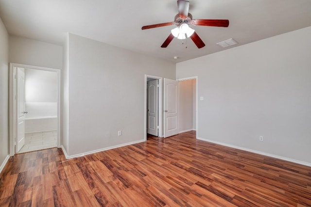 unfurnished bedroom with visible vents, ensuite bathroom, a ceiling fan, wood finished floors, and baseboards