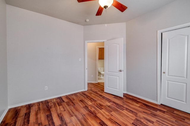 unfurnished bedroom with ceiling fan, wood finished floors, and baseboards