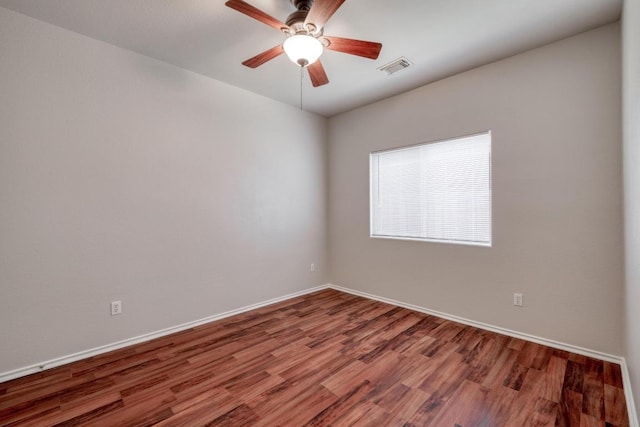 spare room featuring a ceiling fan, visible vents, baseboards, and wood finished floors